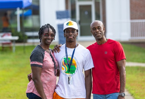 Parents standing with son, posing for picture.