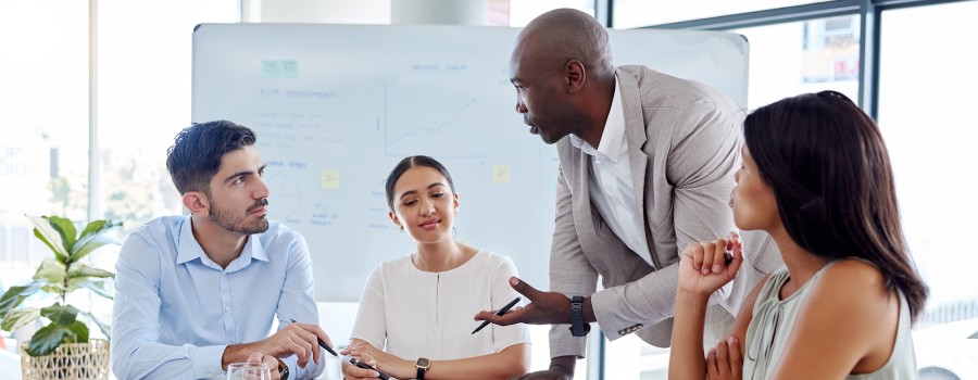 A group of business professionals discuss a project around a table.